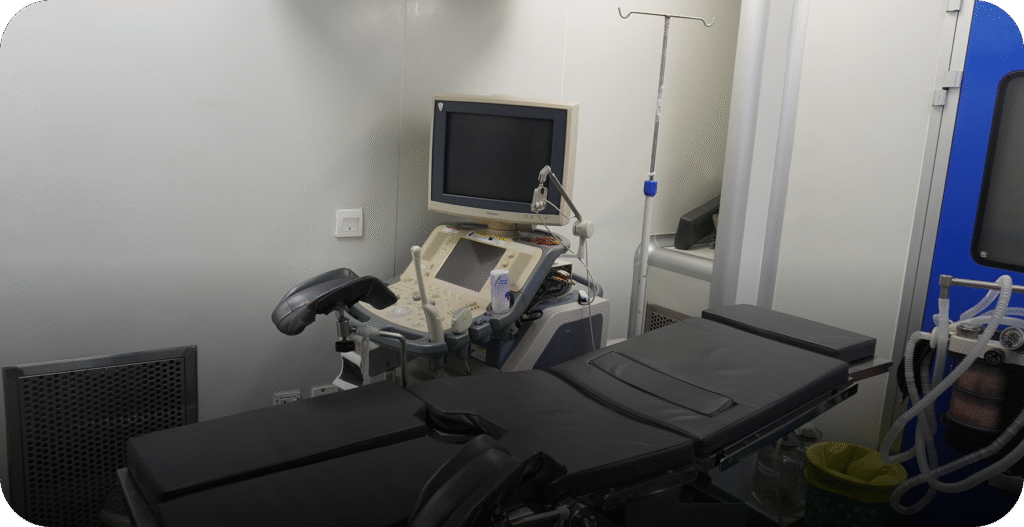 IVF procedure room featuring an examination table and ultrasound guidance system. - AAS Fertility