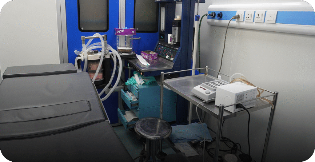 IVF procedure room with an adjustable examination table and anesthesia machine/medical delivery equipment. - AAS Fertility