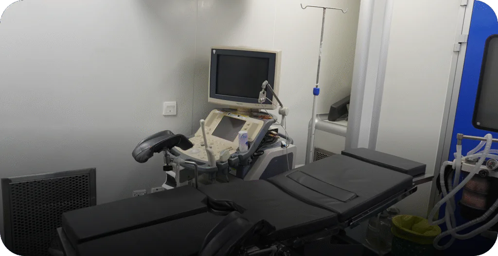 IVF procedure room featuring an examination table and ultrasound guidance system. - AAS Fertility